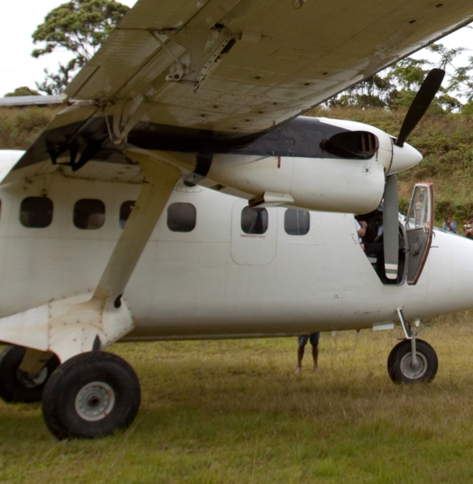Light aircraft on a remote grass airstrip in the Owen Stanley Range, Papua New Guinea